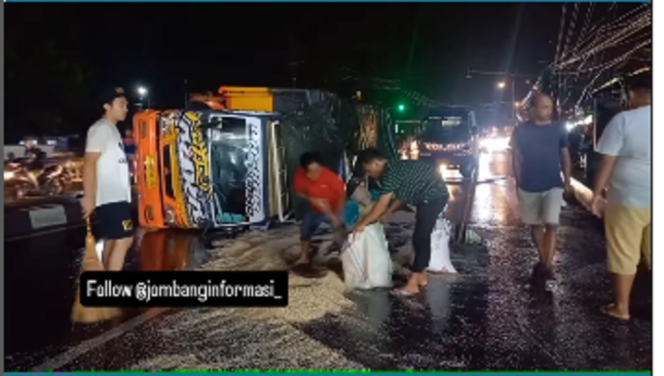 
					Beberapa orang dikerahkan menggnakan sekop untuk mengumpulkan kembali beras yang tercecer akibat truk kecelakaan jalan utama Mojoagung, 9 Desember 2024. tangkap layar video@jombanginformasi_