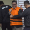 Di depan kamera wartawan Sekjen PDI-P, Hasto Kristiyanto mengangkt kedua tangannya yang diborgor sambil tersenyum, saat konferensi pers di gedung Merah-Putih KPK, Kamis 20 Februari 2025. Tangkap Layar Video Youtube@VivaNews