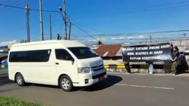 Dua pemudi di Bengkulu berdiri di tepi jalan sambil membentangkan spanduk hitam dengan tulisan mencolok, menggunakan kalimat menohok, 27-28 Mei 2028. Foto: darahjuang.online