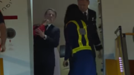 Tampak lengan perempuan mengenakan baju merah mendarat di pipi kanan Presiden Prancis, Emmanuelle Macron, setiba di bandara Hanoi, Minggu malam 25 Mei 2025. Muncul spekulasi, Macron sedang bertengkar dengan istrinya. Tangkap layar video Youtibe@MetroTV