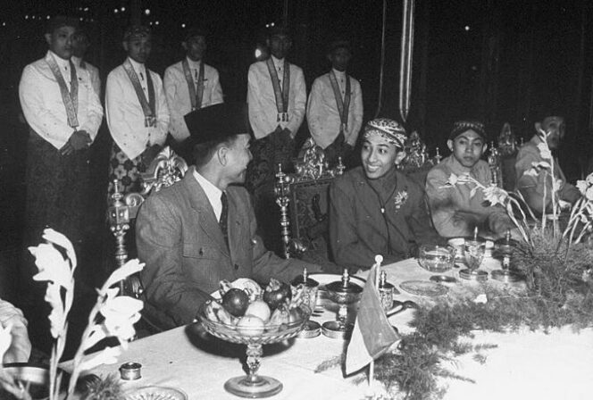 
					Susuhunan Pakubuwana XII menerima kunjungan Presiden Soekarno dan para pejabat pemerintah Republik Indonesia di Sasana Handrawina, Keraton Surakarta, sekitar awal tahun 1946. Tampak duduk di sebelah susuhunan, adalah Adipati Mangkunegara VIII dan R.P. Soeroso.