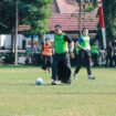 Kapolres Jombang saat berusaha menendang bola dengan mengenakan sarung
