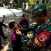 Babinsa menempelkan stiker merah putih di pipi anak-anak- desa siswa SDN Kromong, kecamatan Ngusikan, lokasi TMMD 125 Jombang 2015, jelang persiapan lomba-lomba Agustusan. Foto: Diskominfo Jombang