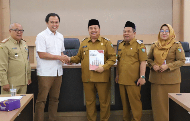 
					Peneliti dari Universitas Brawijaya Dr. Helmy Adam, SE, MSA, AK. menyerahkan hasil riset eveluasi tiga BUMD kepada Bupati Jombang, Warsubi, Senin 13 Oktober 2025. Foto: jombangkab.go.id