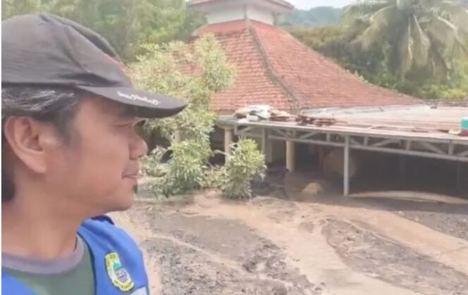 
					Warga menunjukkan sebuah masjid di Dusun Sumberlangsep yang terlihat sebagian atapnya karena diterjang banjir lahar Semeru pada Minggu (7/12/2025). Foto: Antara