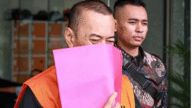 Bduiman bayu Prasojo tampak malu memperlihatkan wajhanya, saat digiring ke KPK. Ia ditangkap terkait kasus impot barang KW, sebagai pegawai  DJDB, Jakarta Utara, Kamis 26 Februari 2026. Foto: cines.id