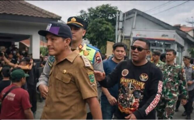 
					Polisi tampak menggiring Kades Hoho Alkaf kekuar dari polsek, pasca penggeroyokan yang dilakukan anggota LSM Harimau, Rabu 10 Maret 2026. Foto: ist