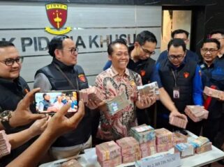 Wagiyo Santoso Aspidsus Kejati Jatim menunjukkan uang yang diamankan dari kantor dan rumah ketiga tersangka yang terlibat dalam kasus dugaan pungutan liar di lingkungan Dinas ESDM Jatim. Foto: Akira suarasurabaya.net 