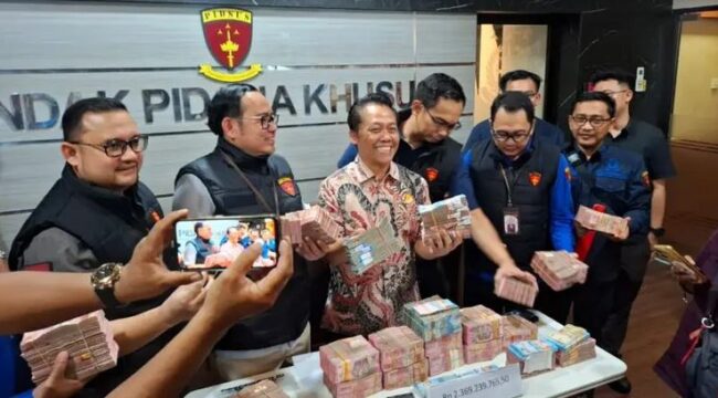 Wagiyo Santoso Aspidsus Kejati Jatim menunjukkan uang yang diamankan dari kantor dan rumah ketiga tersangka yang terlibat dalam kasus dugaan pungutan liar di lingkungan Dinas ESDM Jatim. Foto: Akira suarasurabaya.net 