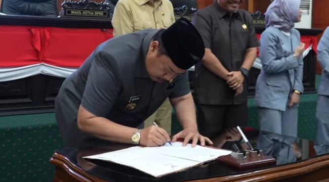 Bupati Jombang H Warsubi menandatangangi naskah rekomendasi dari DPRD tentang LPKJ APBD 2025, dalam sidang paripurna di gedung DPRD Jombang, Senin 20 April 2026. Foto: Instagram@dprd_jombang