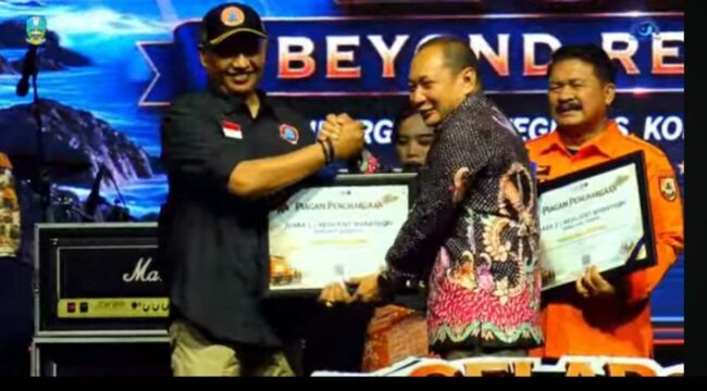 BPBD Jombang di tengah suasana serba terbatas, akan tetapi tetap mengukir prestasi besar, tampil sebagai juara I dalam lomba dan kompetisi Resilient Marathon dan Penanggulangan Kebencanaan Jatim 2026. Kalaksa BKBD Jombang, (Kiri) Wiku Birawa Felipe Diaz Quintas, S.STP., M.Si, menerima piagam penghargaan sebagai Juara I Jawa Timur, di Pacitan, 20-24 Juli 2026. Foto: ist